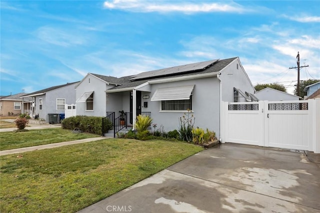 bungalow with a gate, fence, solar panels, stucco siding, and a front lawn