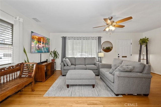 living room featuring plenty of natural light, ceiling fan, visible vents, and wood finished floors