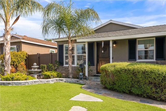 view of front of house featuring fence, stone siding, a gate, stucco siding, and a front yard