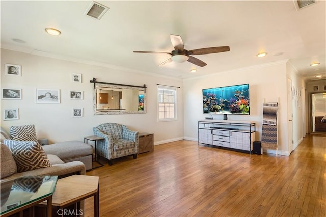 living area with ceiling fan, ornamental molding, wood finished floors, and visible vents