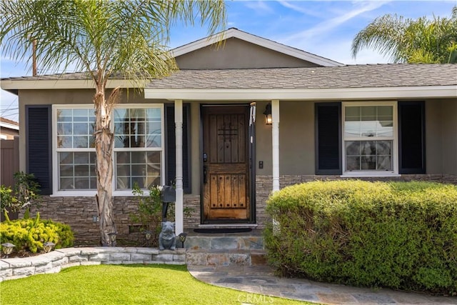 property entrance featuring stone siding, a shingled roof, and stucco siding