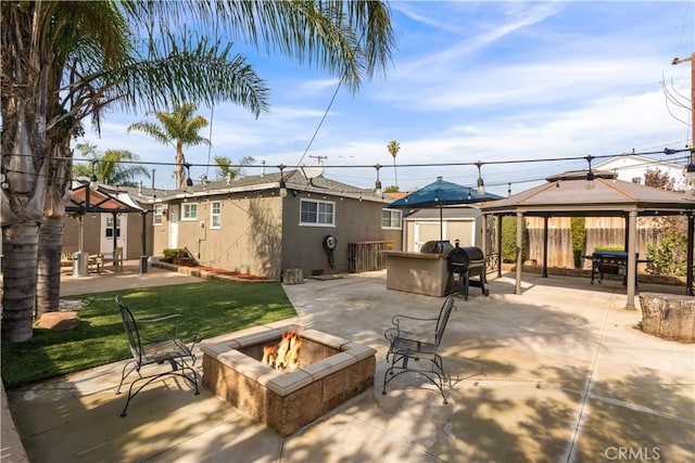 view of patio / terrace with a fire pit, a gazebo, fence, an outdoor structure, and a shed