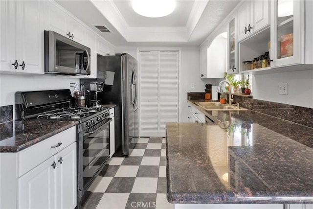 kitchen featuring dark floors, stainless steel appliances, a sink, visible vents, and a tray ceiling