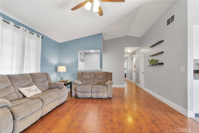 living area featuring lofted ceiling, wood finished floors, a ceiling fan, visible vents, and baseboards