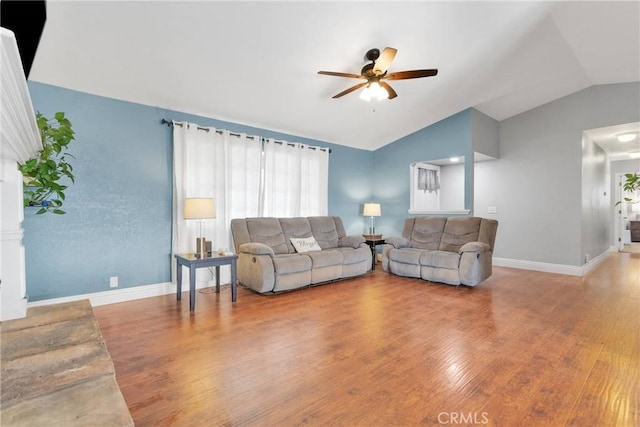 living room featuring vaulted ceiling, ceiling fan, wood finished floors, and baseboards