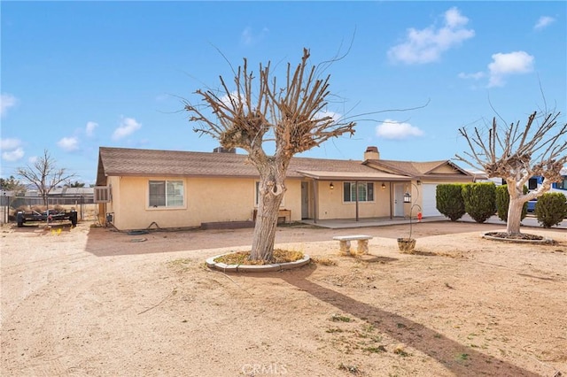 view of front of property featuring a garage, fence, and stucco siding