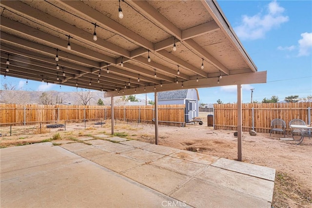 view of patio with a storage shed, a fenced backyard, and an outdoor structure