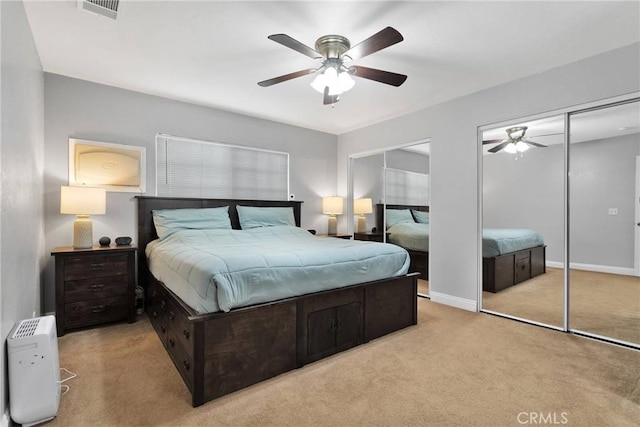 carpeted bedroom featuring a ceiling fan, visible vents, baseboards, and two closets