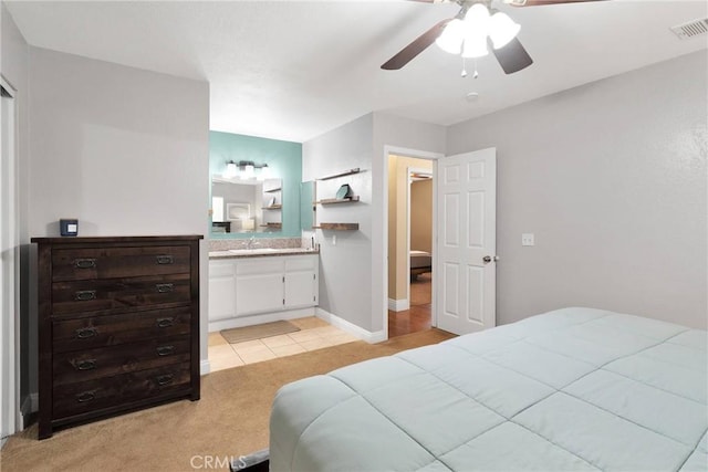 bedroom featuring light carpet, a sink, visible vents, a ceiling fan, and ensuite bath