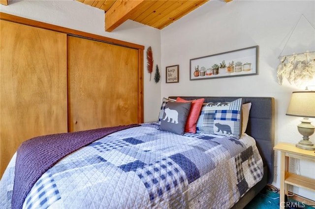 bedroom featuring beamed ceiling, wooden ceiling, and a closet