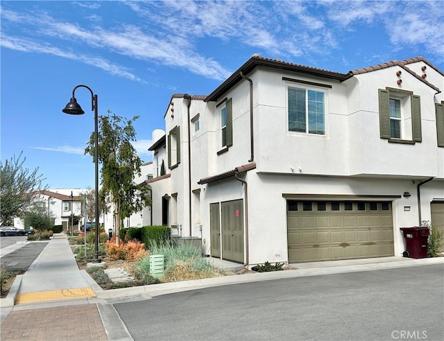 view of front of property with a tiled roof, an attached garage, and stucco siding