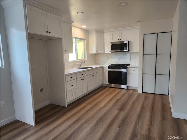 kitchen with gas range oven, stainless steel microwave, a sink, and white cabinets