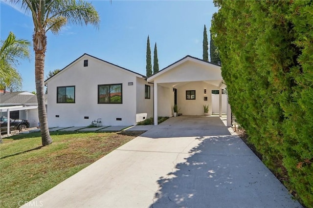 view of front facade with driveway, stucco siding, an attached carport, crawl space, and a front yard