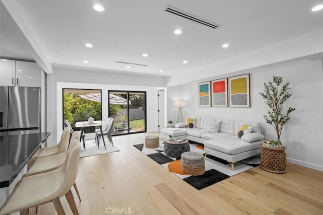 living room with light wood finished floors, baseboards, visible vents, and recessed lighting