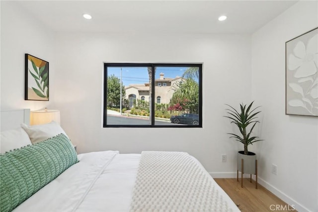 bedroom with baseboards, wood finished floors, and recessed lighting