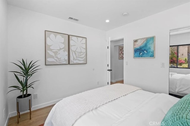 bedroom with recessed lighting, visible vents, baseboards, and wood finished floors