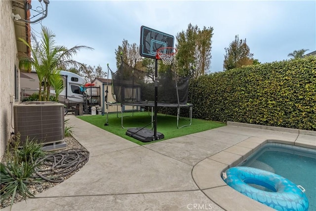 view of sport court featuring a trampoline, a fenced in pool, and a lawn