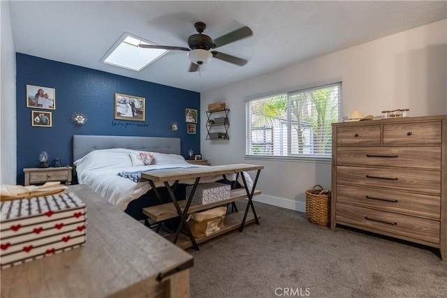 bedroom featuring carpet floors, a skylight, ceiling fan, and baseboards