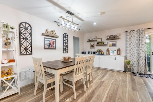 dining room with visible vents, light wood-style flooring, and an inviting chandelier