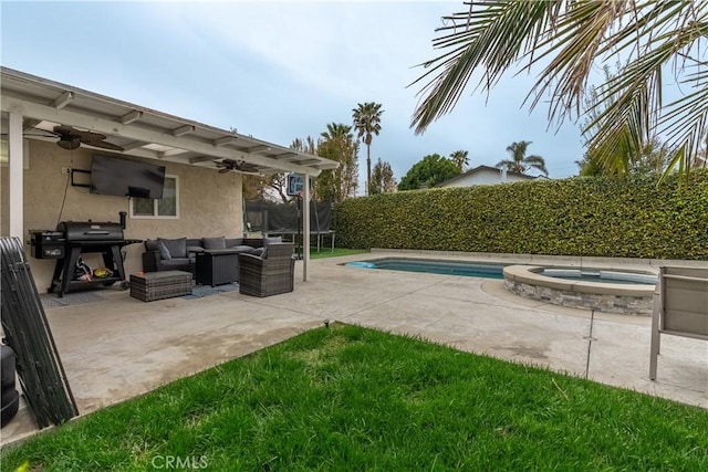 view of patio with a ceiling fan, area for grilling, a trampoline, a pool with connected hot tub, and an outdoor living space