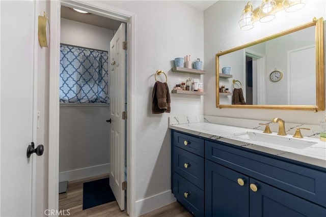 bathroom with wood finished floors, vanity, and baseboards