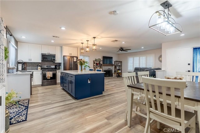 kitchen with a fireplace, stainless steel appliances, light countertops, visible vents, and white cabinetry