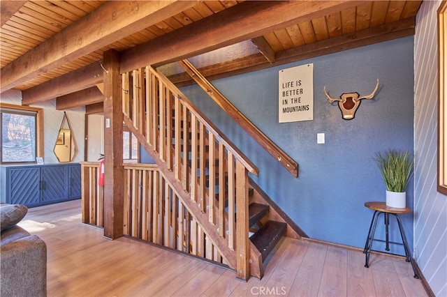 staircase featuring wood-type flooring, beam ceiling, and a healthy amount of sunlight