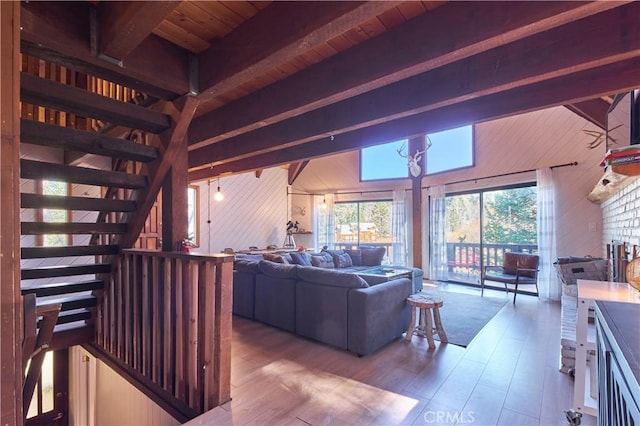 living area featuring wood walls, stairs, beam ceiling, and wood finished floors