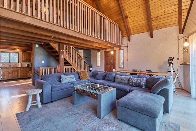 living area featuring wooden ceiling, wood walls, wood finished floors, stairs, and beam ceiling