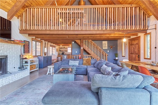 living area featuring stairway, a fireplace, wood finished floors, and wood ceiling