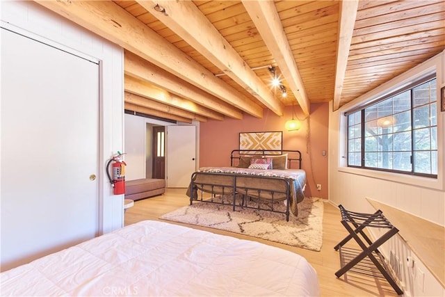 bedroom featuring light wood finished floors, wood ceiling, and beam ceiling