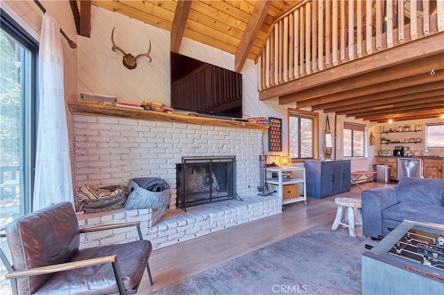 living area featuring vaulted ceiling with beams, a brick fireplace, wooden ceiling, and wood finished floors