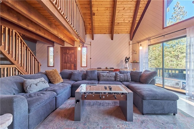 living room with wooden walls, wooden ceiling, stairway, high vaulted ceiling, and beam ceiling