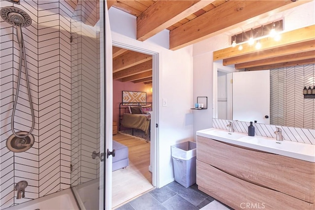 full bath featuring double vanity, a sink, beam ceiling, and connected bathroom