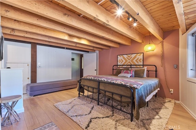 bedroom featuring beamed ceiling, rail lighting, wood ceiling, and light wood-style floors