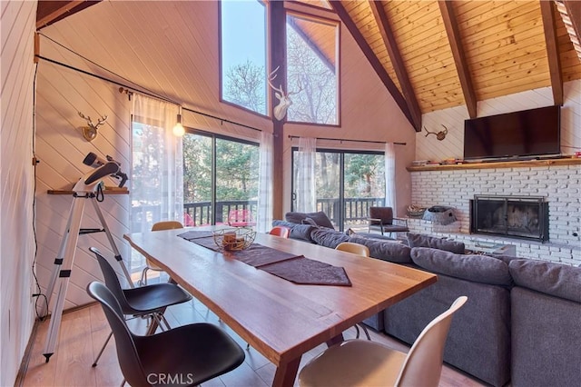 dining room featuring wood walls, a fireplace, wood finished floors, wood ceiling, and beam ceiling