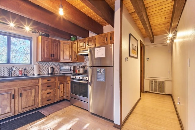 kitchen featuring under cabinet range hood, a sink, visible vents, appliances with stainless steel finishes, and dark countertops