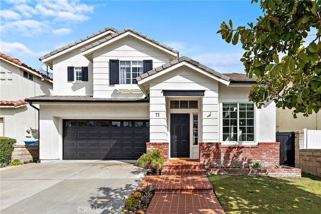 view of front of property with brick siding, fence, driveway, and an attached garage