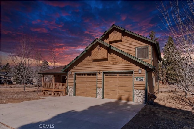 view of front of property featuring an attached garage, stone siding, and concrete driveway