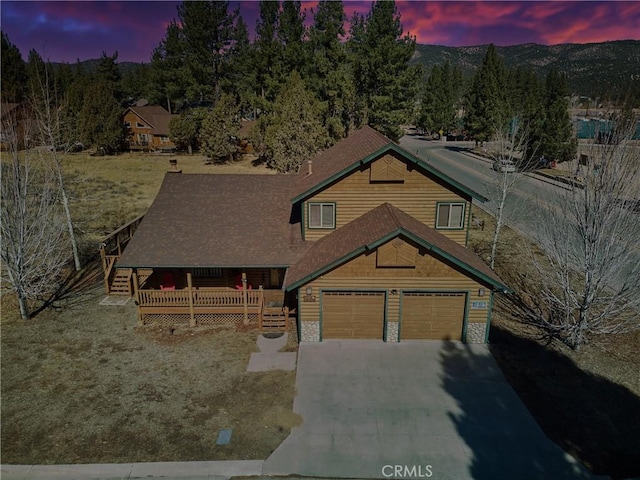 view of front of property with an attached garage, stone siding, concrete driveway, and a wooden deck