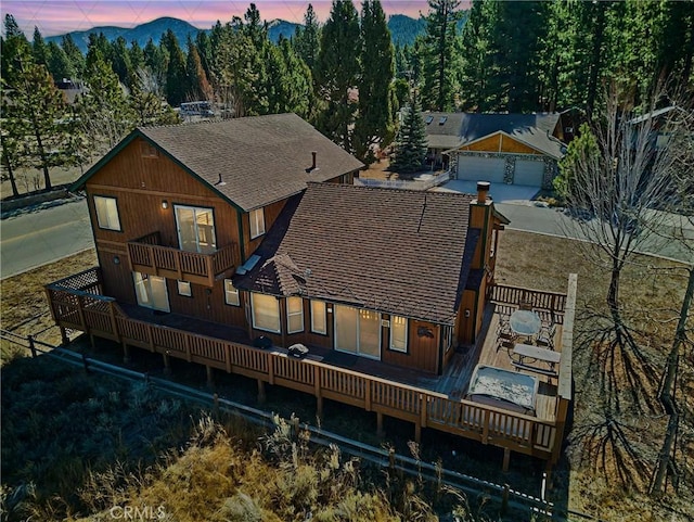 back of property with a garage, roof with shingles, and a balcony