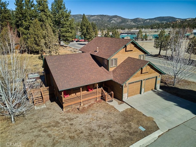 view of front of house featuring a garage, roof with shingles, a mountain view, and driveway