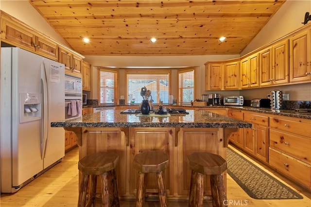 kitchen with lofted ceiling, white appliances, a breakfast bar area, and wood ceiling