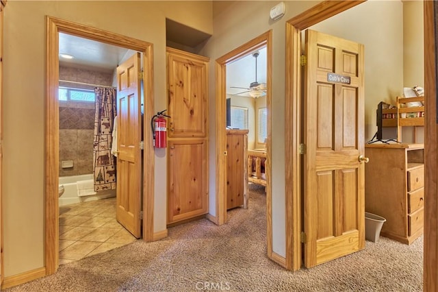 hallway with light carpet, baseboards, and light tile patterned floors