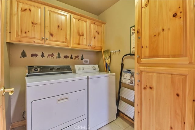 laundry area with cabinet space, light tile patterned floors, and washer and clothes dryer