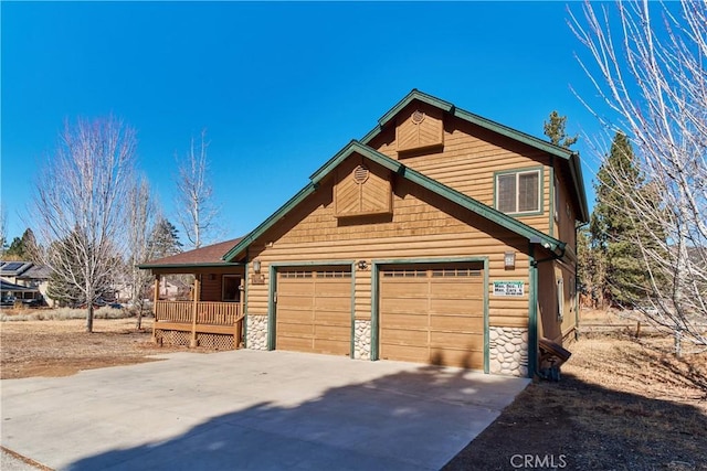 view of front of house with driveway, stone siding, and an attached garage