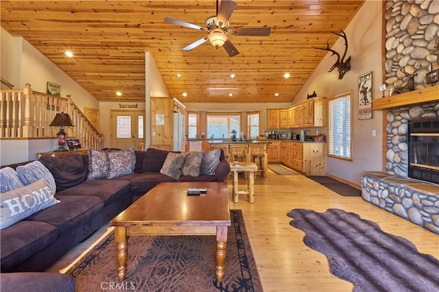 living area featuring light wood-style flooring, wood ceiling, a fireplace, and stairway