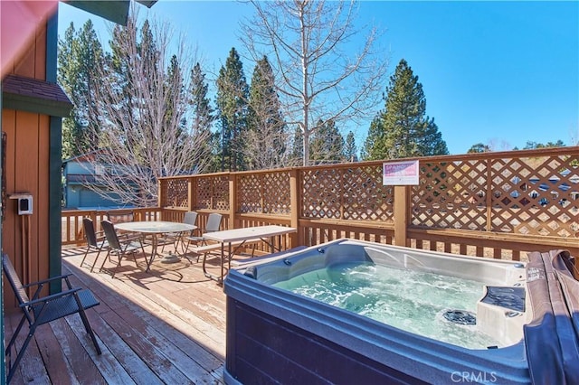 wooden terrace with an outdoor hot tub and outdoor dining space