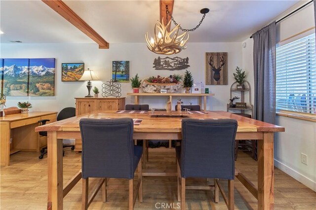 dining room with visible vents, baseboards, light wood-style floors, a chandelier, and beam ceiling