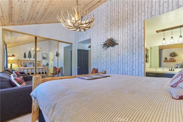 bedroom with wallpapered walls, wooden ceiling, ensuite bathroom, a chandelier, and a closet